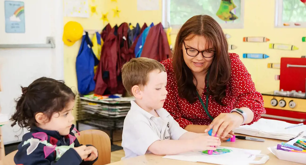 A teacher supporting two pupils in class