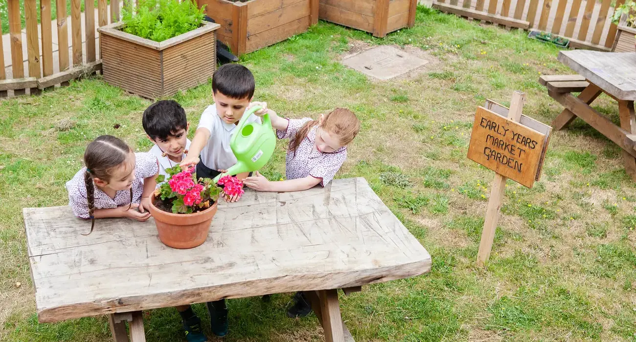 Junior School pupils watering plants in the garden