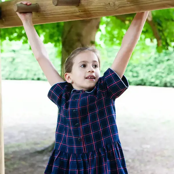 A young pupil swinging on the monkey bars in our adventure playground